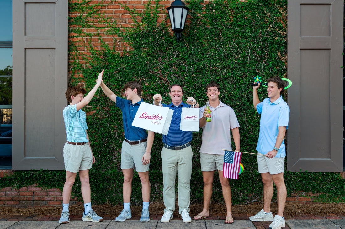 A group of males holding various items from Smith's Variety