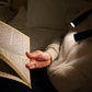 A person using the hands-free booklight around their neck to read a book
