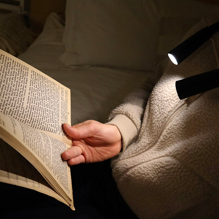 A person using the hands-free booklight around their neck to read a book
